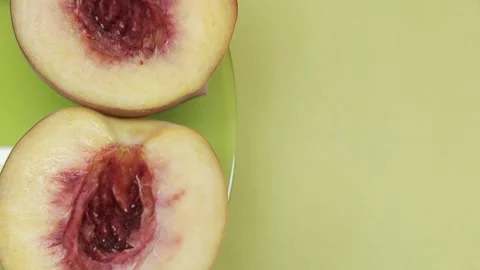 Close-up half of peach fruit with stone rotates on a green-yellow background Stock-Footage 136853630