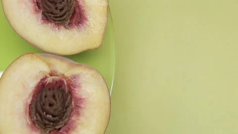 Close-up half of peach fruit with stone rotates on a green-yellow background Stock Footage 137970946
