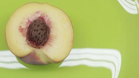Close-up half of peach fruit with stone rotates on a green-yellow background Stock Footage 137970951