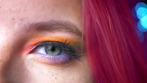 Close-up half-portrait of pink-haired female colourful eye make-up on blurred Video stock 99606305