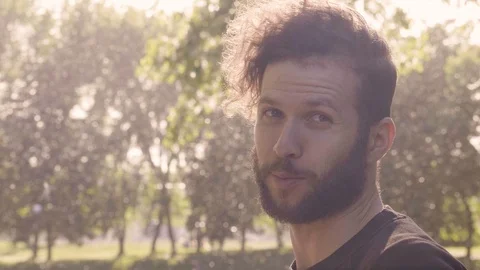Close-up half-turned portrait of a charismatic bearded man who smiling, looking Stock Footage 99427307