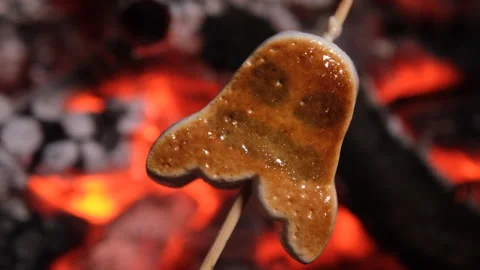 Close-up of a Halloween ghost marshmallow roasting on a wooden skewer over Stockbeeldmateriaal 347382341