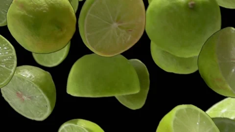 Close-up of the halves of ripe limes falling diagonally on the black background Stock Footage 212737624