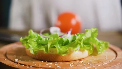 Close up: Hamburger cutlet falling onto a bun and salad. Slow motion Stock-Footage 111345876