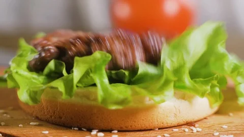 Close up: Hamburger cutlet falling onto a bun and salad. Slow motion 스톡 동영상 111345983