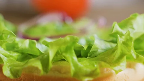 Close up: Hamburger cutlet falling onto a bun and salad. Slow motion 스톡 동영상 111346347