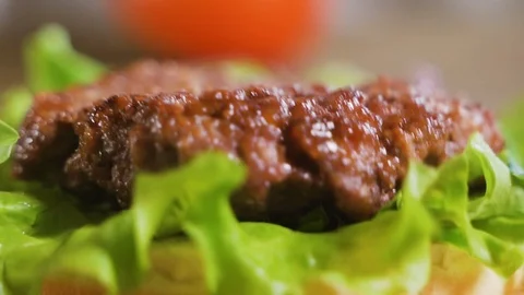 Close up: Hamburger cutlet falling onto a bun and salad. Slow motion Vidéo 111346359