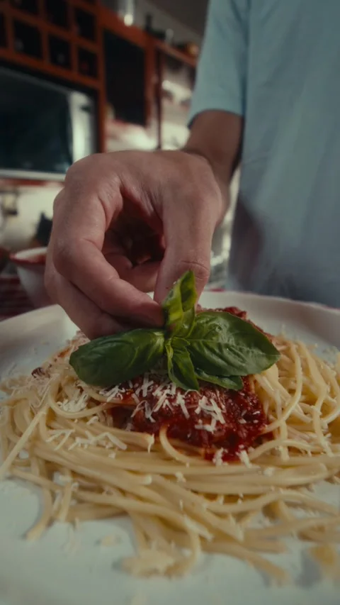 Close-up of hand adding basil to spaghetti Stock Footage 334223076