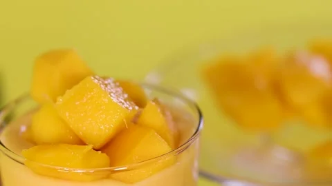 Close Up of Hand Adding Fresh Mango Cubes to Glass Stock Footage 329145001