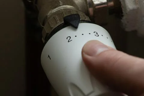 Close up hand adjusting heating temperature. Reducing heating cost in crisi.. Foto stock