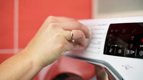 Close-up of hand adjusting program selector on washing machine with digital Stockbeeldmateriaal 289699392
