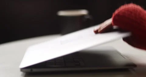 Close-up of a hand adjusting a red knitted scarf on a laptop keyboard Stock Footage 339072994