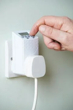 Close Up Of Hand Adjusting Timer Switch In Plug Socket Stock Photos