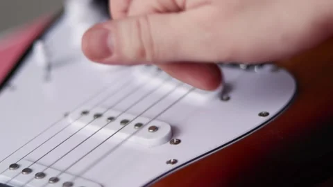 Close-up of a hand adjusting the volume knob on an electric guitar Stock Footage 339191060