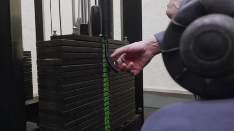 Close up of hand adjusting weight pin on black gym machine weight stack Stock Footage 324755457
