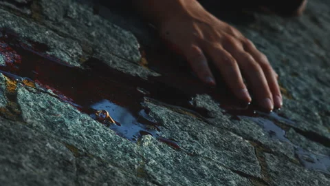 Close-up of hand and blood on stone. Stock footage. Killing man with pool of Stock Footage 245947016