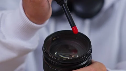 Close-up of Hand Applying Lens Cleaning Solution to Camera Lens for Maintenance Stock Footage 337454079