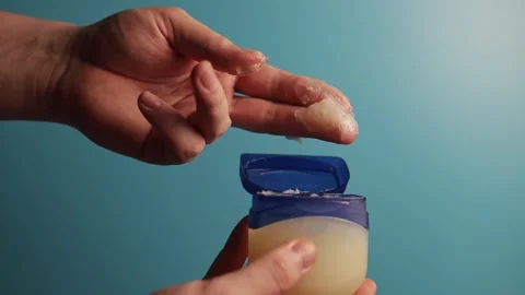 Close-up of hand applying petroleum jelly from a blue container Stock Footage 340268045