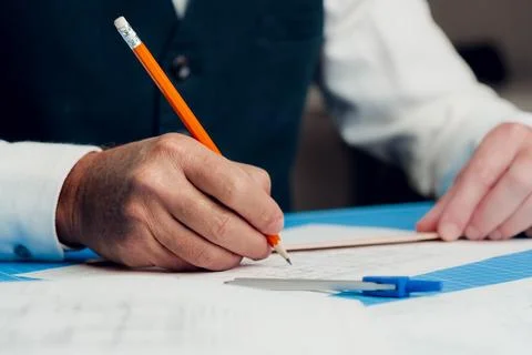 Close up of hand of an architect, engineer drawing blueprint Stock Photos