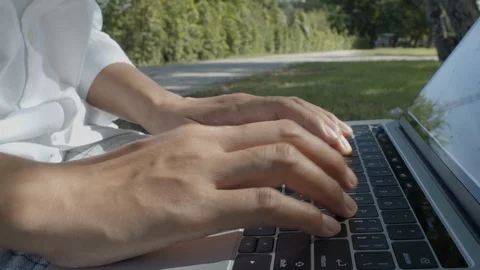 Close-up of hand are using laptop and typing keyboard in the park Stock Footage 115818676