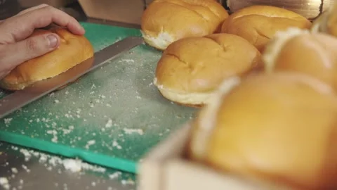 Close-up of hand arranging fresh bread rolls on a cutting board, preparing for 스톡 동영상 332617505