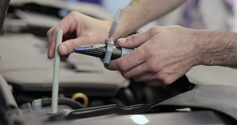 Close up hand of auto mechanic checks the quality of antifreeze in a car Stock Footage 341870969