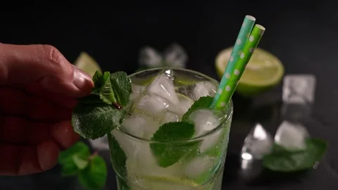 A close-up of the Hand of a bartender Decorating a Sprig of Mint Mojito Cocktail Video stock 237436386