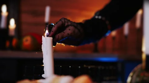 Close-up of a hand in a black glove setting fire to a candle using a match. Stock Footage 285227655