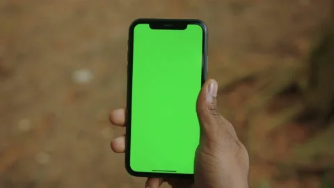 Close-up of the hand of a black man with a mobile phone with a green screen Stock Footage