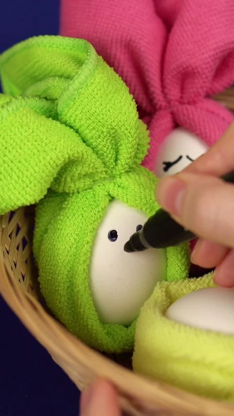 Close-up hand with black marker draws facial features on an Easter egg. Video stock 269544583