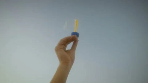 Close-up of a hand blowing soap bubbles in the wind against the sky on a sunny Stock Footage 95965387