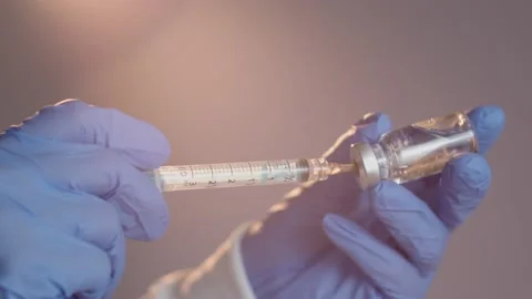 Close-up hand with blue gloves drawing vaccine from vial into syringe Stockbeeldmateriaal 152722270
