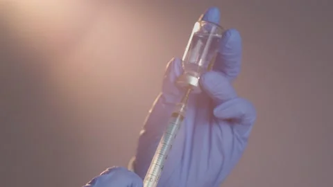 Close-up hand with blue gloves drawing vaccine from vial into syringe Stockbeeldmateriaal 152722306