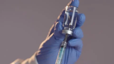 Close-up hand with blue gloves drawing vaccine from vial into syringe Stockbeeldmateriaal 152722368
