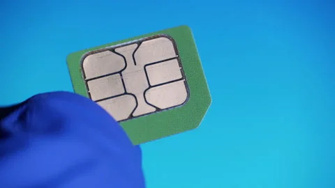Close-up hand in blue gloves holding green micro SIM card on blue background Stock Footage 130814093