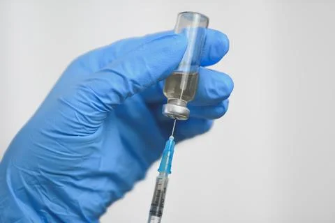 Close-up of a hand in blue gloves is taking medicine into a syringe Stock Photos