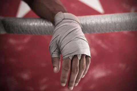 Close up of hand of boxer leaning on ropes on a boxing ring. Stock Photos