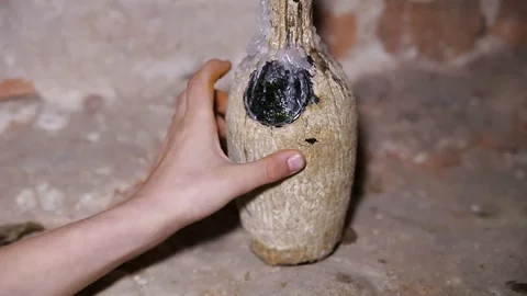 Close up hand boy touch old bottle with candle in a dirty brick basement Stock Footage 98645486