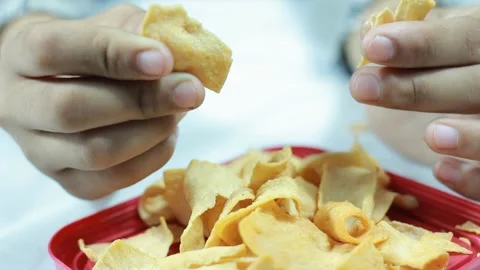 Close-Up of Hand Breaking a Yellow Spicy Chip Stock Footage 279337398