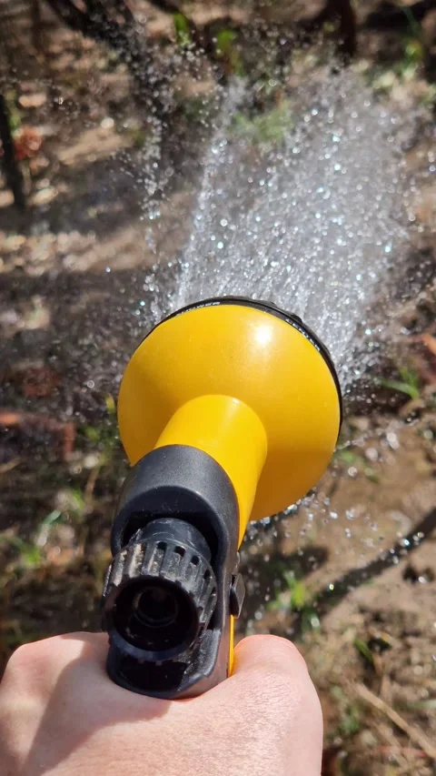 Close-up of a hand with a bright yellow and black water sprayer during water Vídeo Stock 344806541