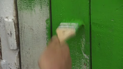 Close-up. hand with a brush. green paint is applied to a wooden door, a fence. Video stock 132048411