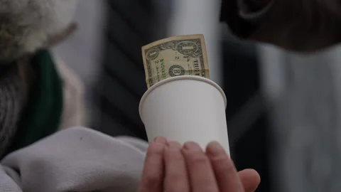 Close-up hand of businessman inserting one-dollar bill into white paper cup held Stock Footage 289744133
