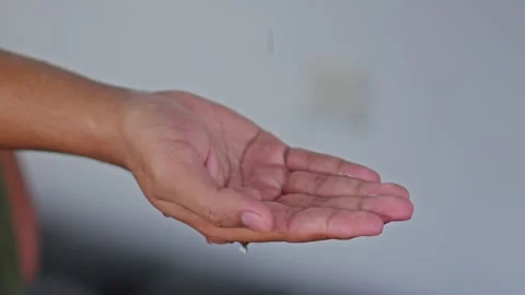 Close-up of hand catching water droplets from ceiling leak Stock Footage 331327679