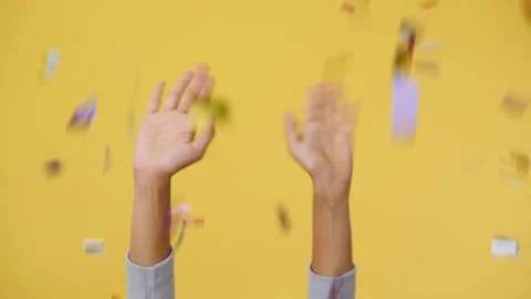 Close up hand Celebrating Flying falling colorful confetti isolated yellow Stock Footage 147612910