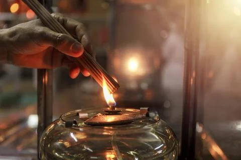 Close up hand cense joss stick with Oil lamp fire. With film grain effect Stock Photos