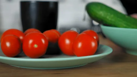 Close up hand chef man takes fresh cherry tomato from bowl with kitchen table Stock Footage 148091842
