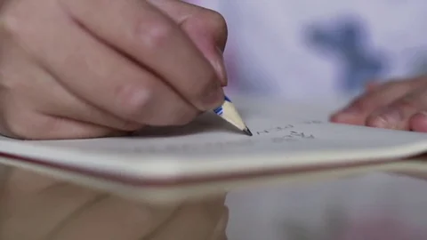 Close up hand children hand holding pencil and doing homework at home Stock Footage