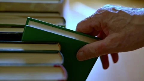 Close-up of a hand choosing a book from a stack of books to read and learn. Stock Footage 318122318