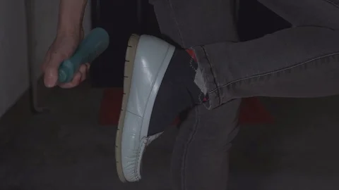Close up of hand cleaning shoe surface with disinfectant spray, slow motion Video stock 129680037