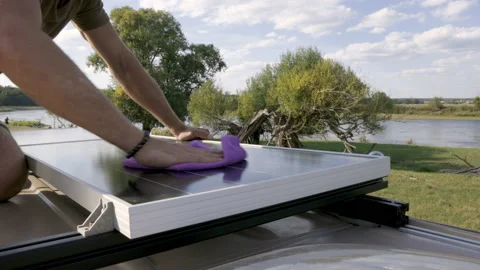 Close-up of a hand cleaning a solar panel on the roof of a camper van Stock Footage 225906013